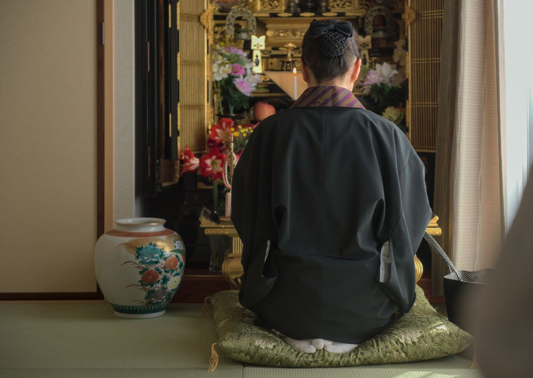 Japanese Woman Buddhist Monk Reciting A Prayer In Front Of A Butsudan