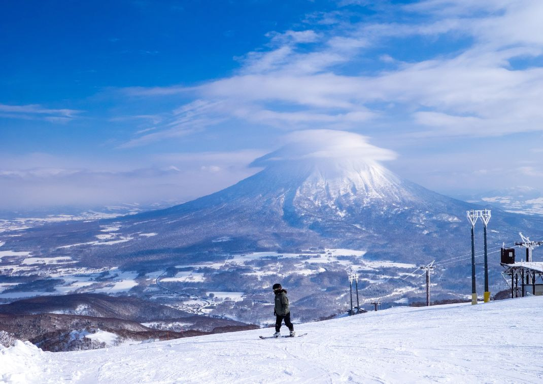 Snowy volcano with cap cloud viewed from a ski resort