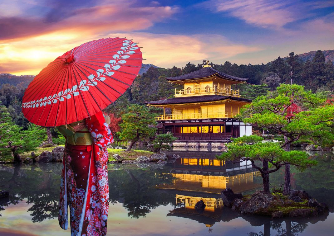 Woman in traditional kimono looking out over the beautiful golden Kinkakuji Temple in Kyoto, Japan