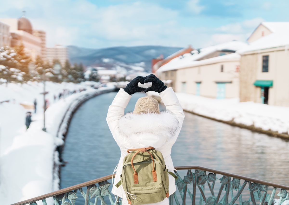 Happy traveller woman with backpack in snowy Otaru