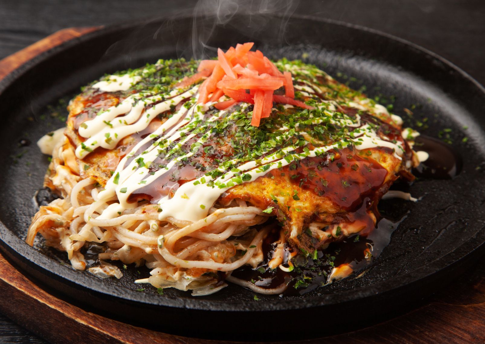 Thick Hiroshima style Okonomiyaki pancake stuffed with noodles and topped with sauces