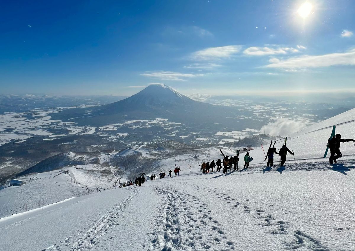 Skiers with a snowy volcano in Niseko, Hokkaido