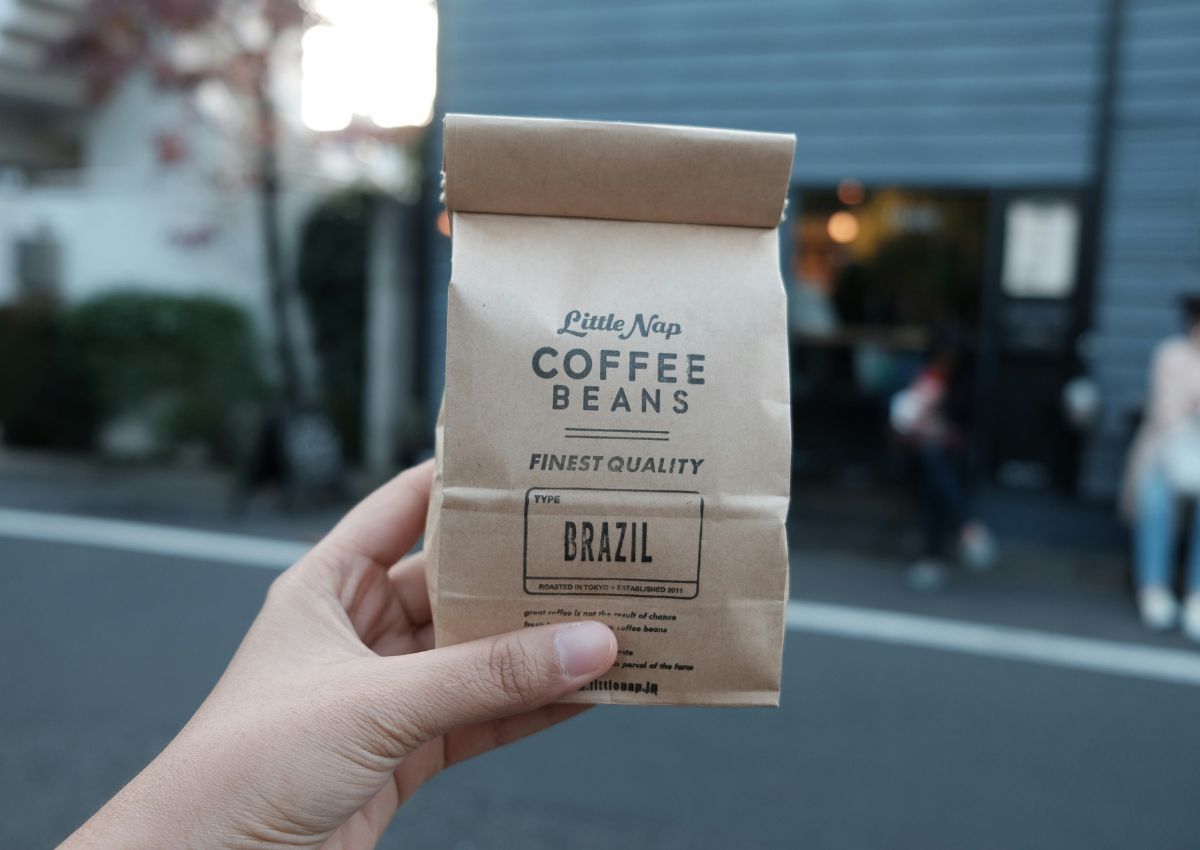 A brown paper bag of Little Nap Coffee Stand coffee beans held outside