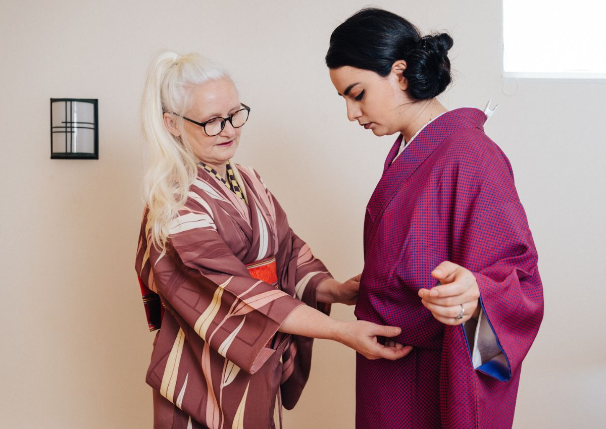 kimono instructor helps dress another woman in kimono