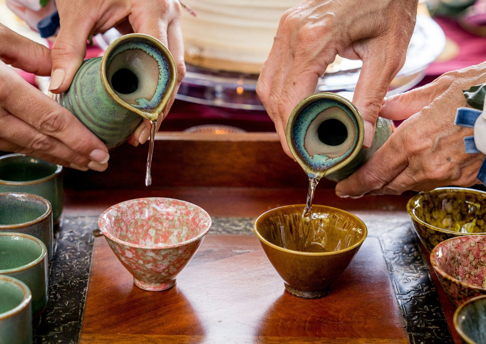 Hot sake being poured into traditional teacups