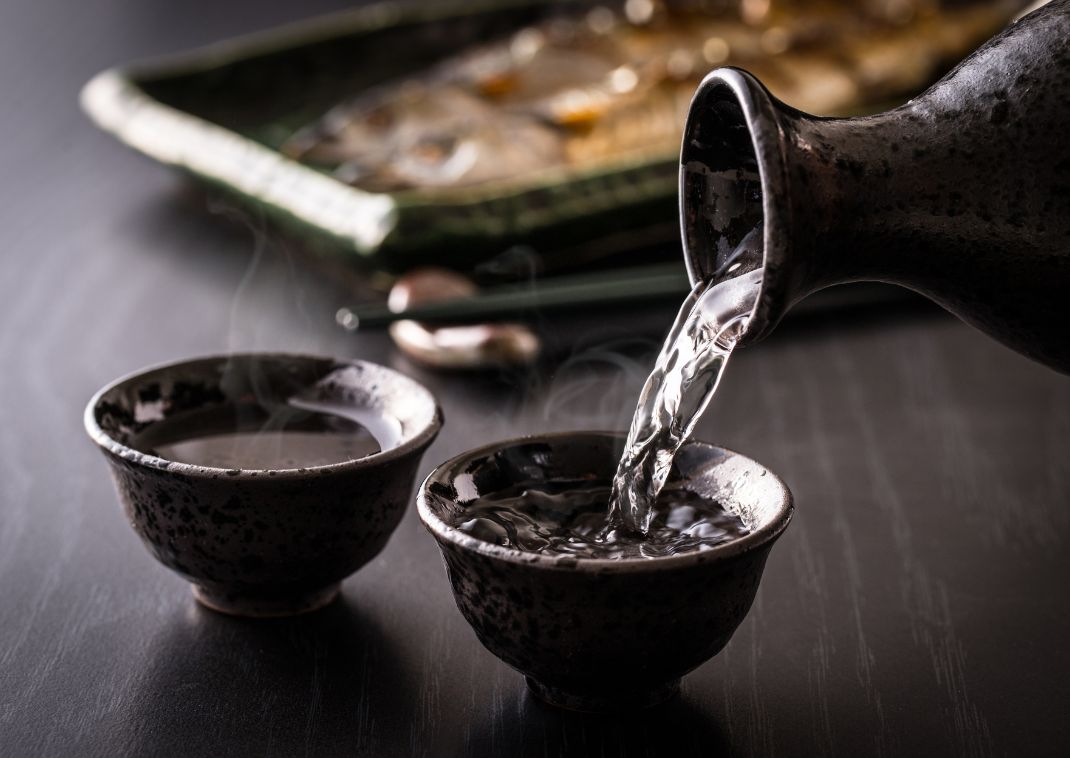 Hot sake being poured into traditional teacups