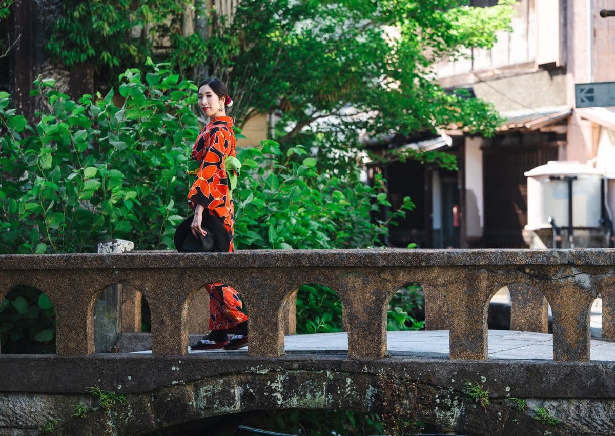 woman in kimono strolls on a bridge in rural Japan