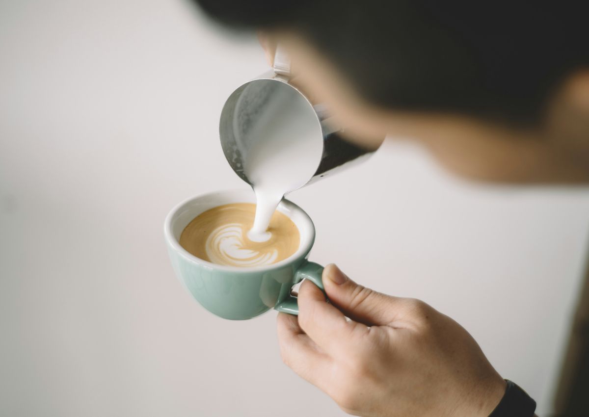 Pouring milk foam into cappuccino mug
