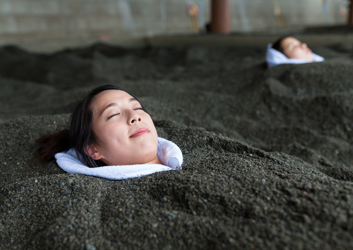 Woman enjoying hot sand bath, Kagoshima, Japan