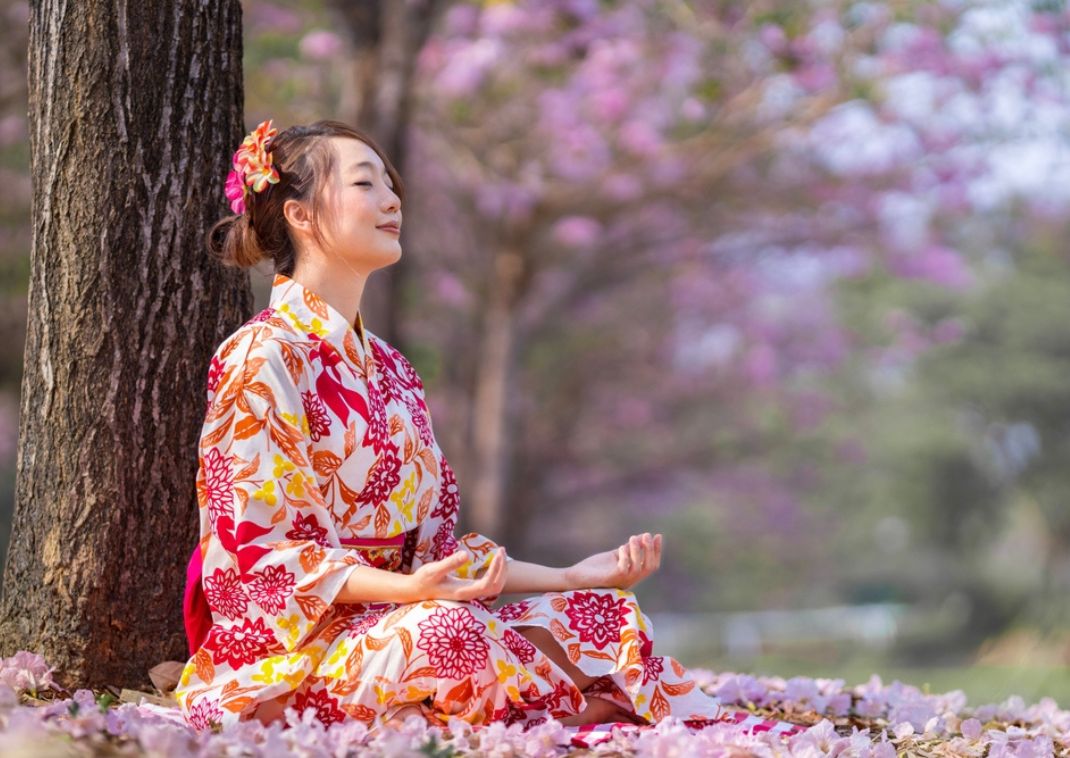  Japanese woman is doing meditation during cherry blossom season for inner peace, mindfulness.