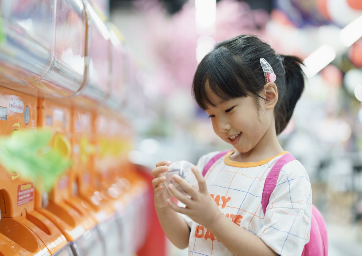 Child girl playing with Japanese gacha machine toy