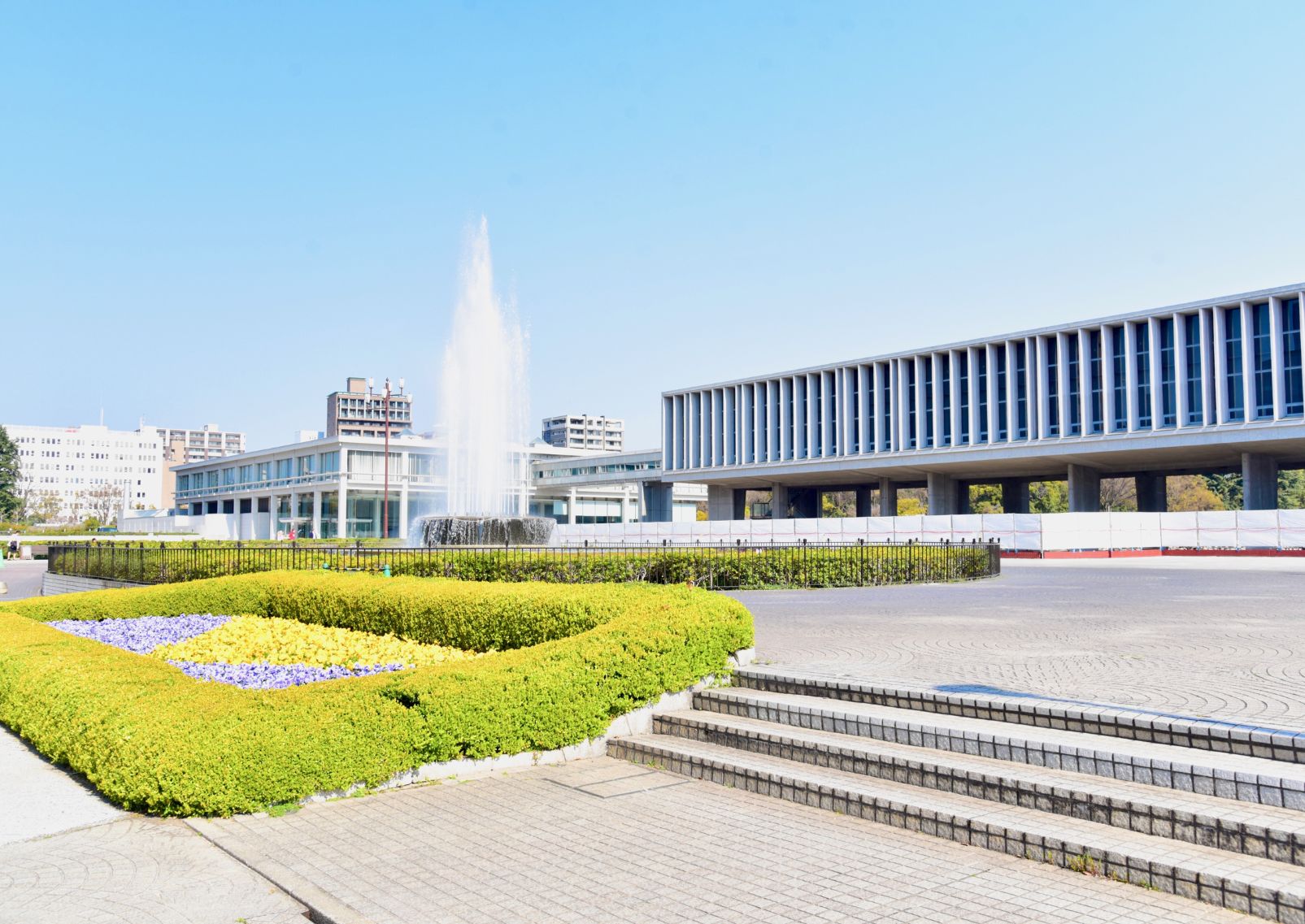  Hiroshima Peace Memorial Museum, a modern concrete and glass building with blue sky reflected in a pool in front