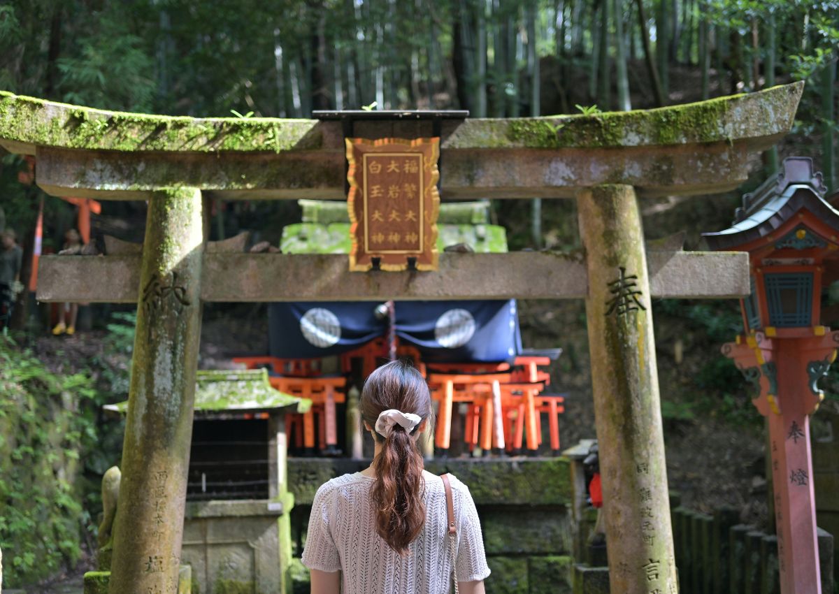 Girl standing in front of torii gate at Fushimi Inari shrine, Kyoto, Japan