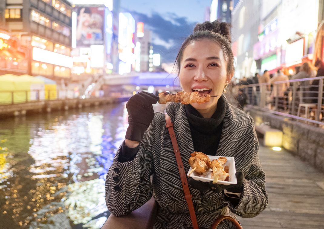 Lady eating Japanese streetfood in Osaka