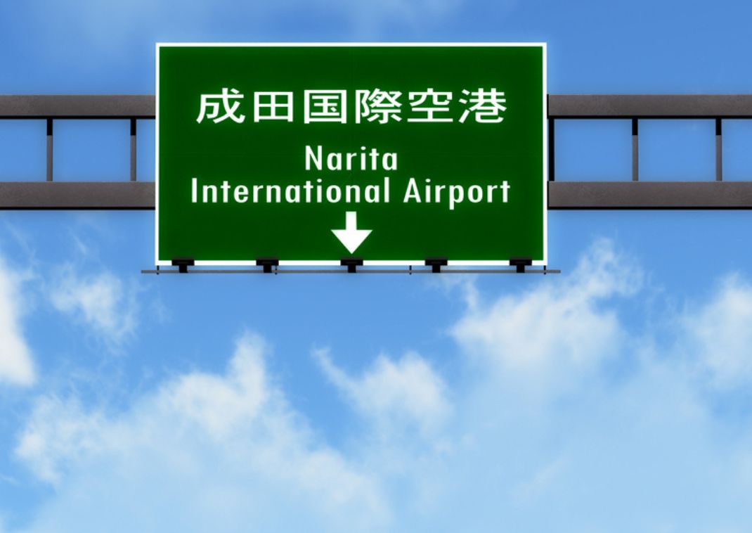  Sign to Narita International Airport on a highway with a blue sky background.