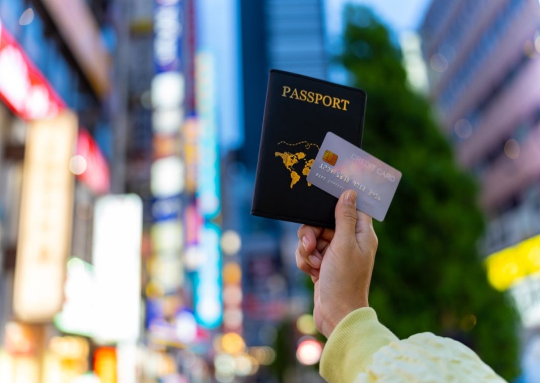 Woman’s hand holding up a passport and credit card in Tokyo