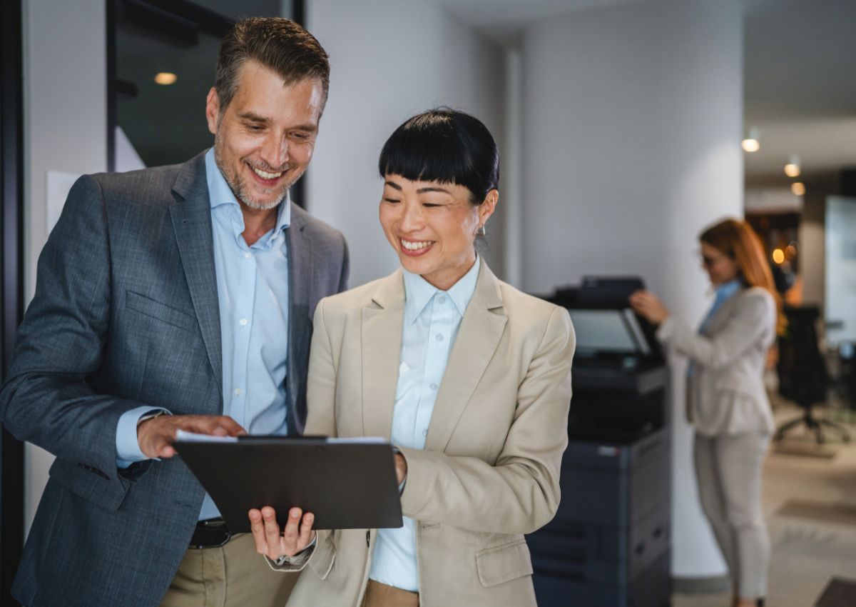  Japanese businesswoman and Caucasian businessman review document on clipboard together
