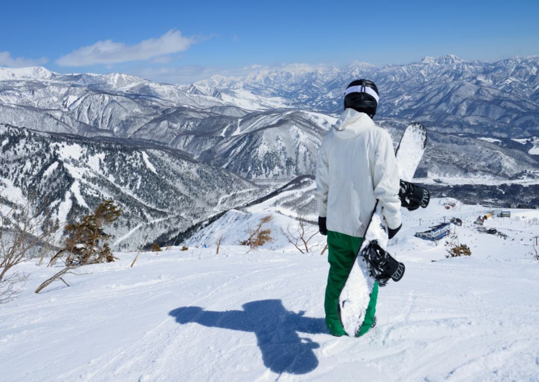 Snowboarder looking over a snowy scene in Hakuba, Japan