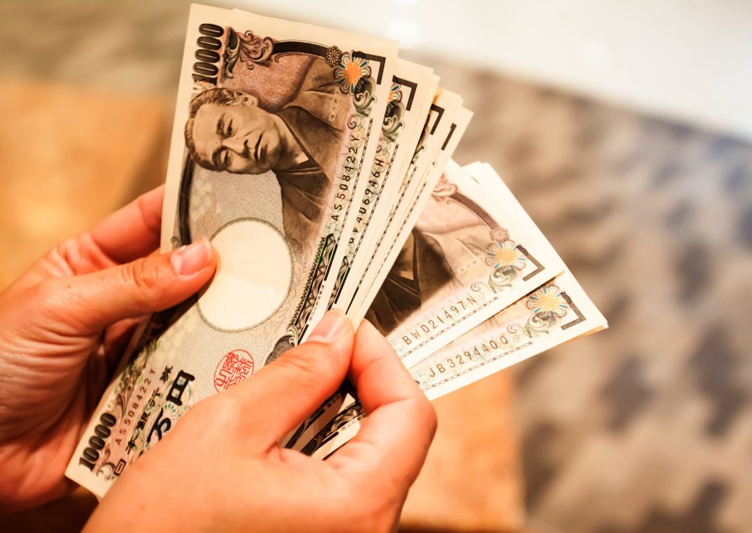 Person fanning a large sum of Japanese yen bank notes