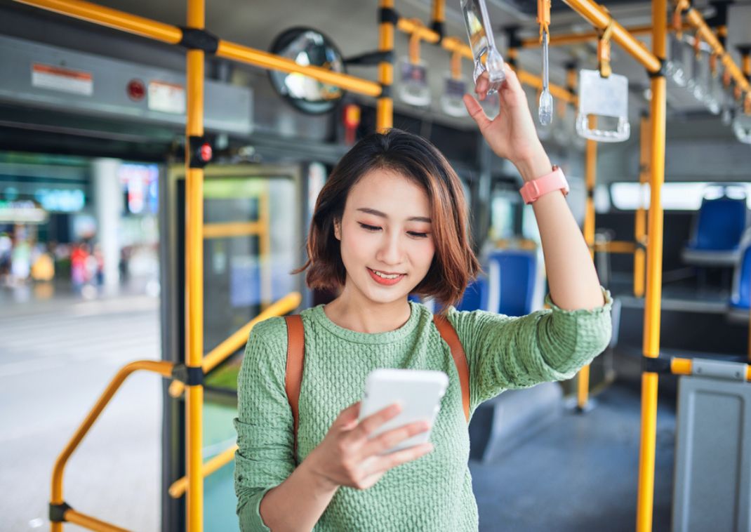 Woman looking at phone while riding a bus in Japan