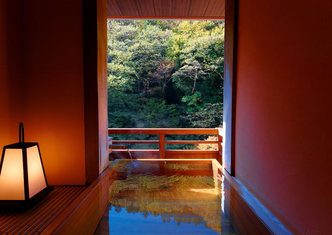 Warm red hotel bathroom looking out onto a forest