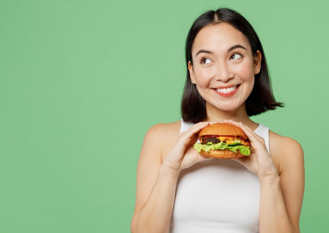 Lady holding a burger on a green background