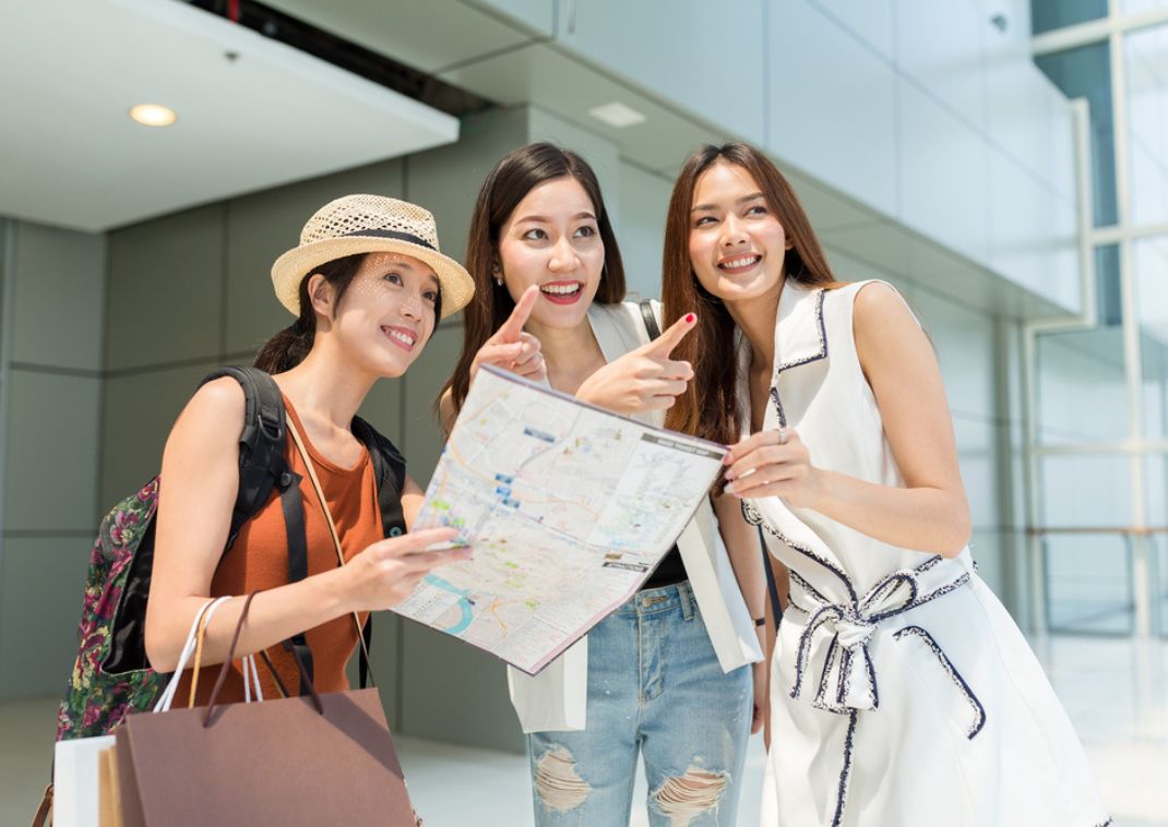 Lady holding map showing two other women where to go in Japan