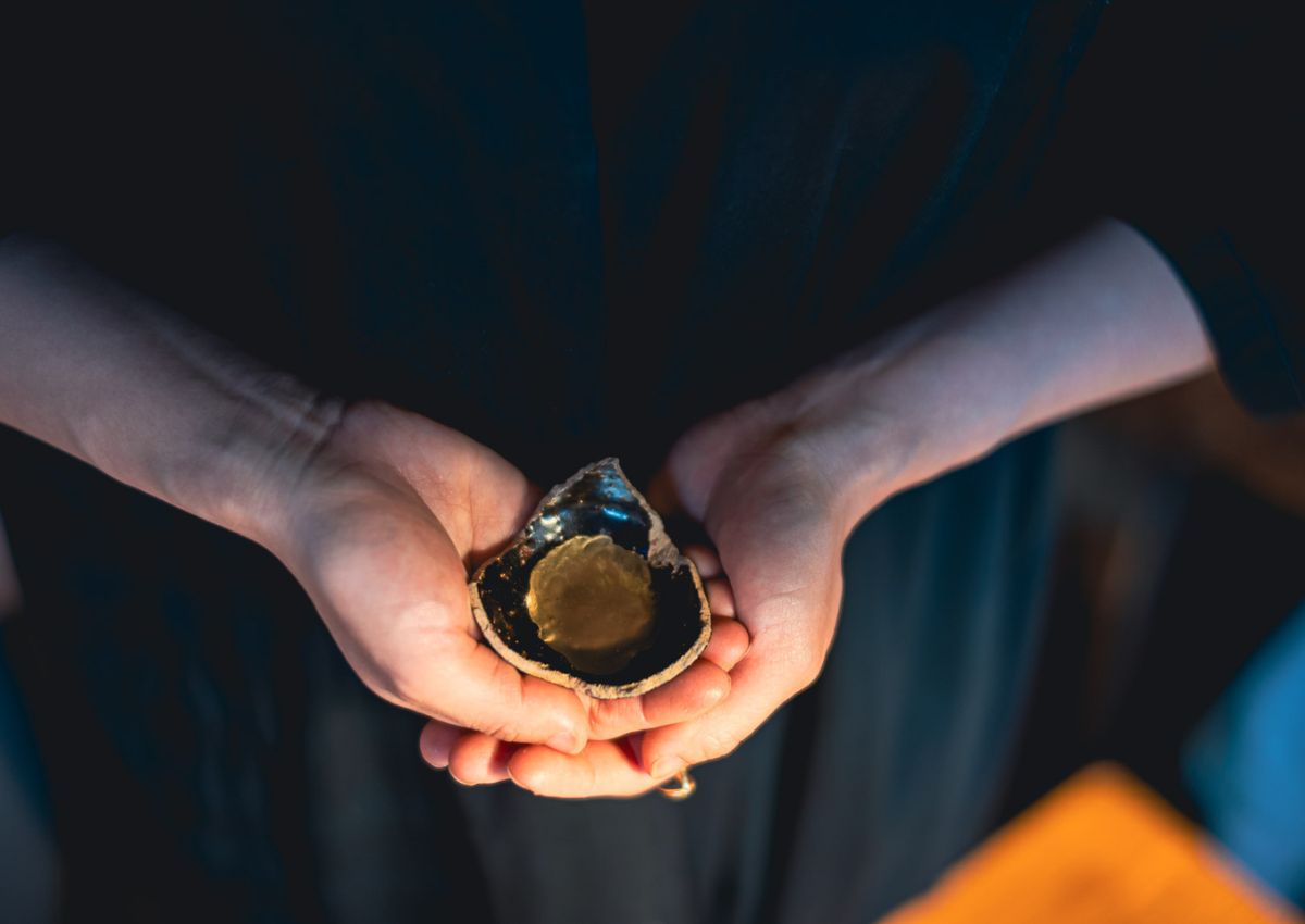 Hands holding broken ceramic with gold lacquer used in Japanese kintsugi
