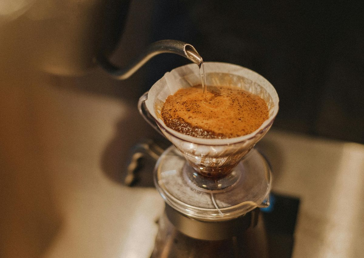 Woman pouring drip-coffee in cup, Japan