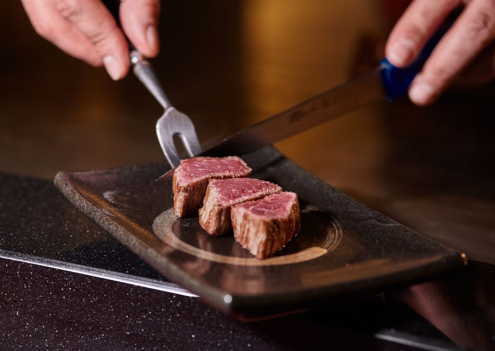 Japanese chef is cooking by hand a sliced delicious Kobe Beef