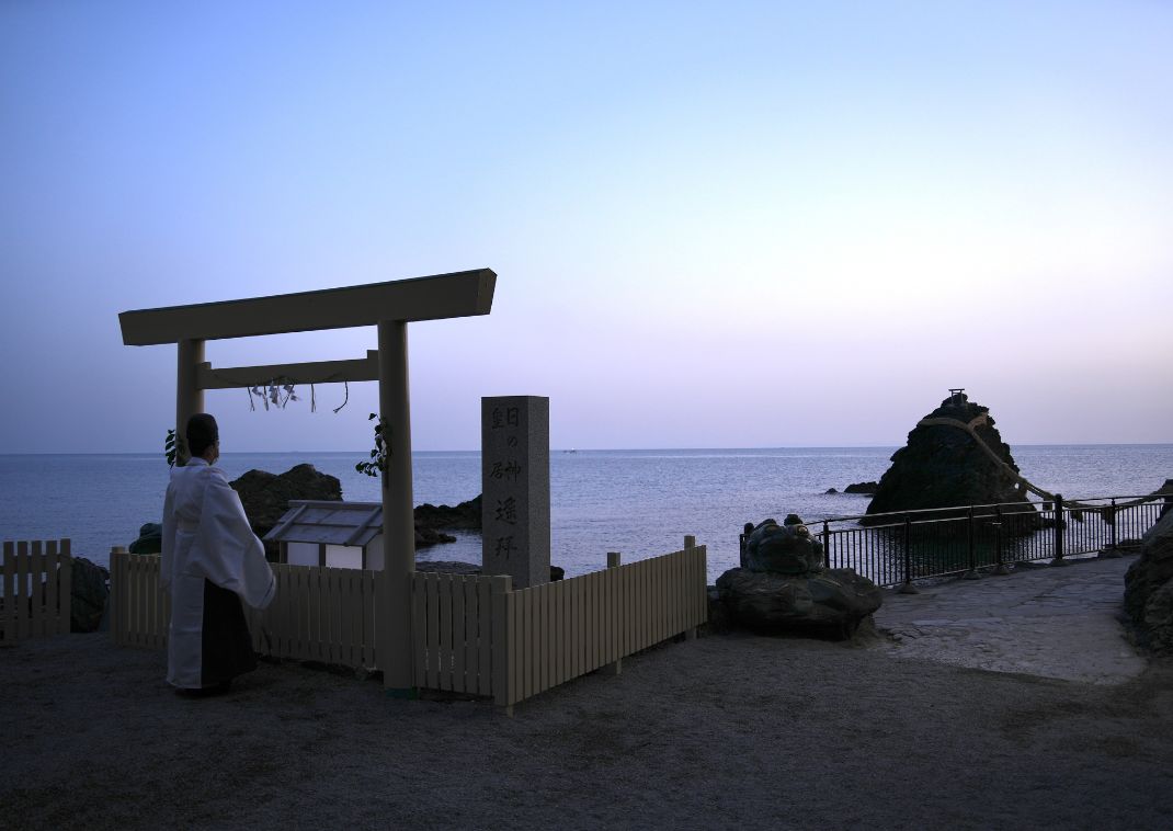 Priest Praying next to Meoto Iwa rocks, Ise, Japan