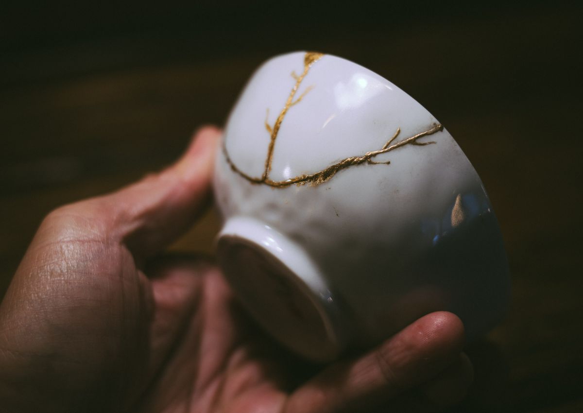 hand holding bowl repaired with gold kintsugi lines