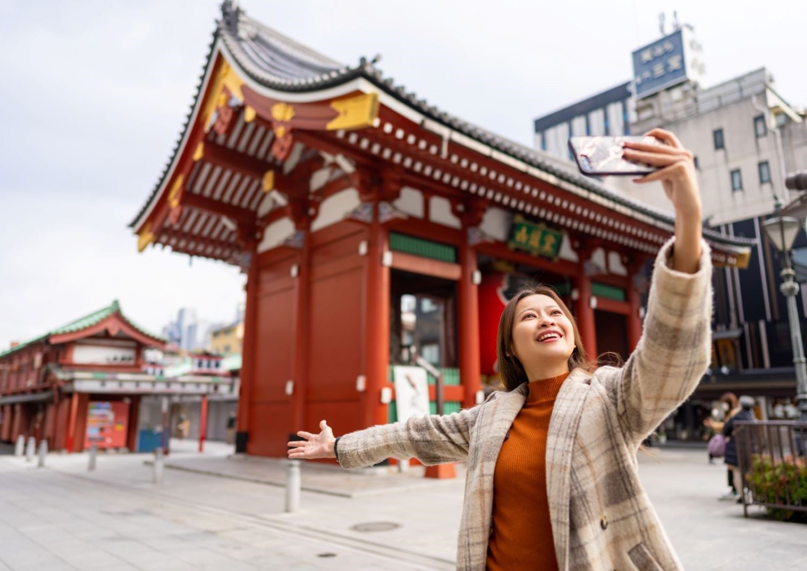 Girl with phone in front of Sensoji Temple, Asakusa, Tokyo, Japan