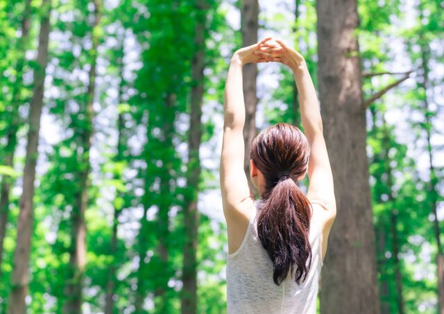 Woman practicing forest bathing in green forest
