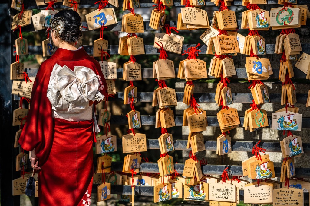 Japanese woman reading prayer cards on a wooden board at Kiyomizu-dera temple in Kyoto