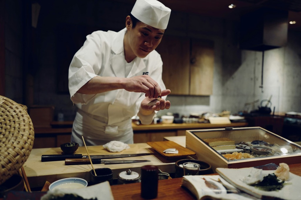 Japanese chef is sashimi in front of the counter bar at a Japanese sushi restaurant