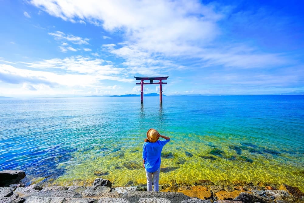 Traveller standing near a torii gate at Lake Biwa in Shiga Prefecture, Japan