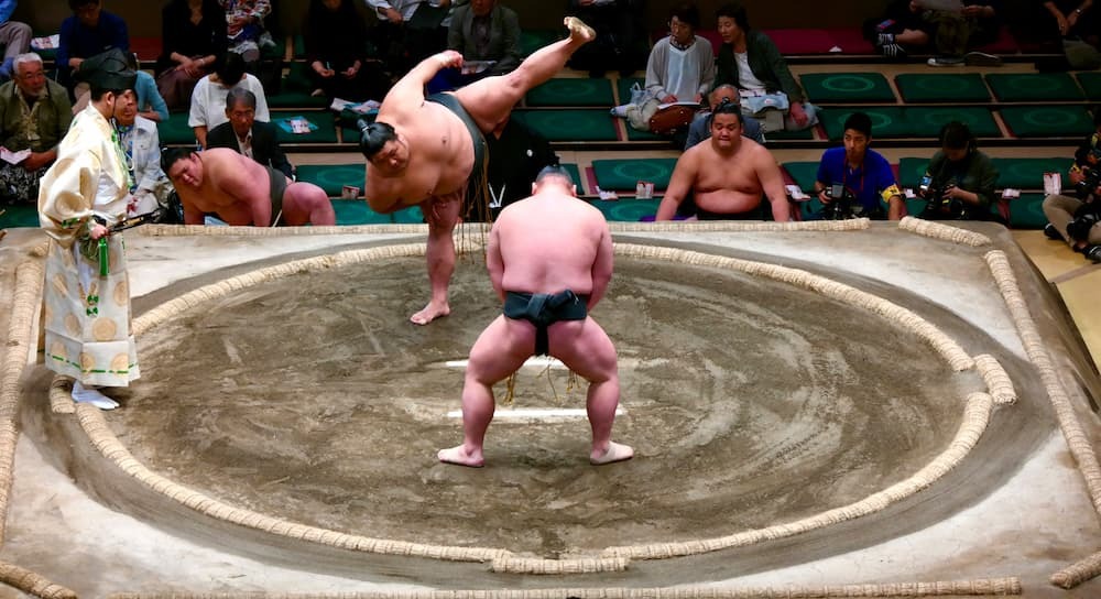 Japanese sumo wrestlers preparing for a match in the ring, wearing traditional mawashi