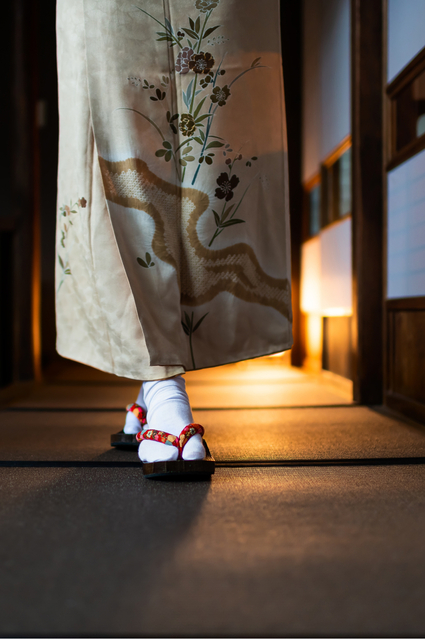 Woman in kimono walking through a traditional ryokan with tatami mats and shoji doors