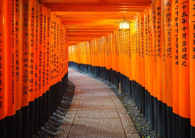 A traditional red Japanese gate torii with black writing in Fushimi Inari Shrine, Kyoto, Japan